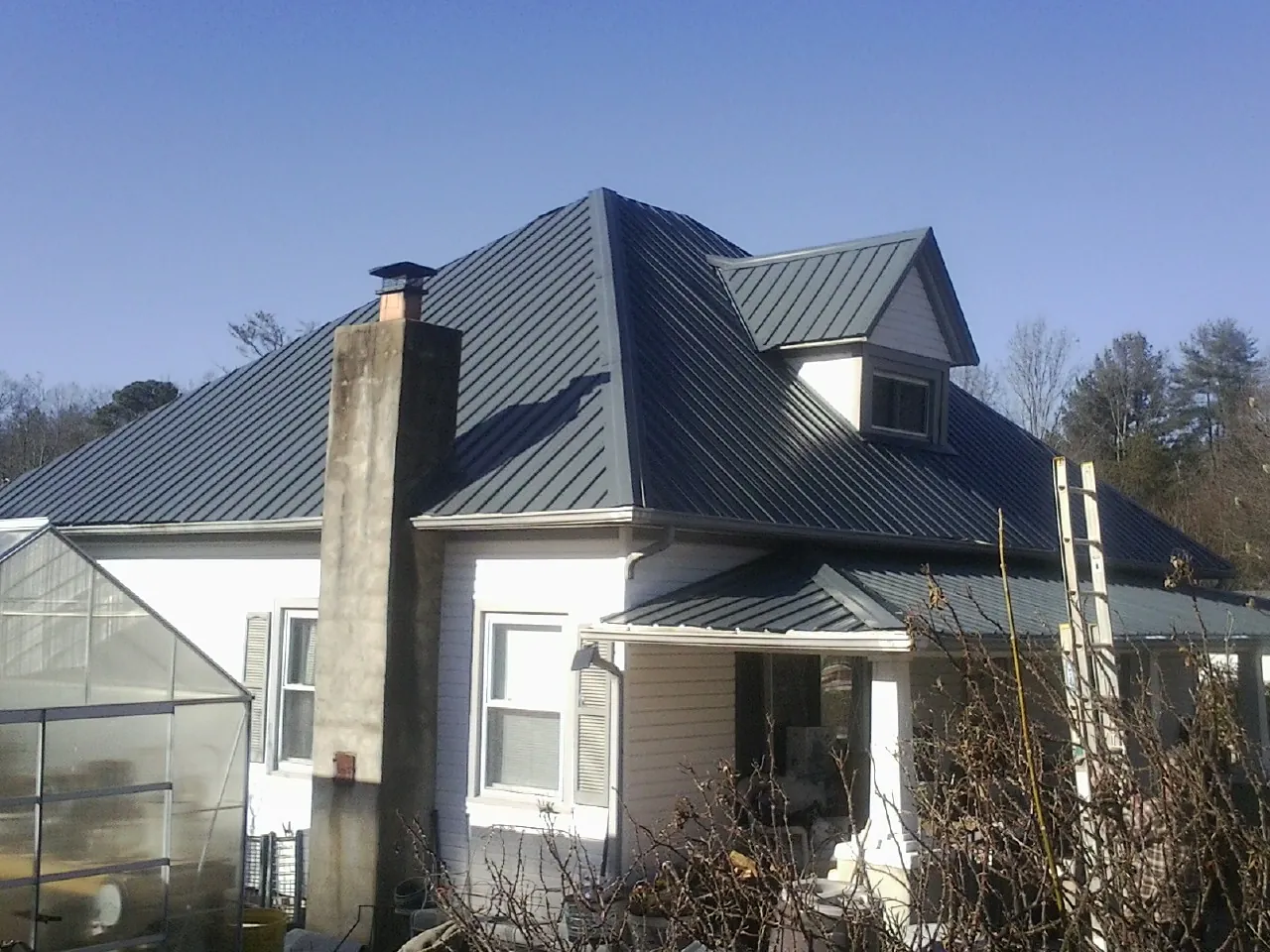 Dark blue standing seam metal roof on a white farmhouse with dormer — Slate & Tile Roof Repair by Roofing Brothers in La Center