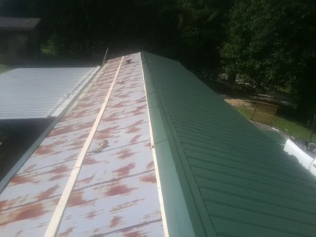 Old rusted panels beside newly installed green metal roofing — Wind Damage Roof Repair by Roofing Brothers in La Center