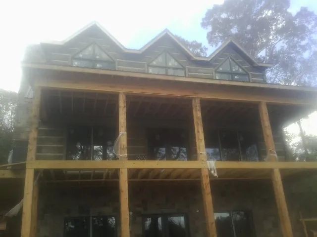 Dormers and porch framing on a large log home under construction — Roof Coating work by our crew in La Center