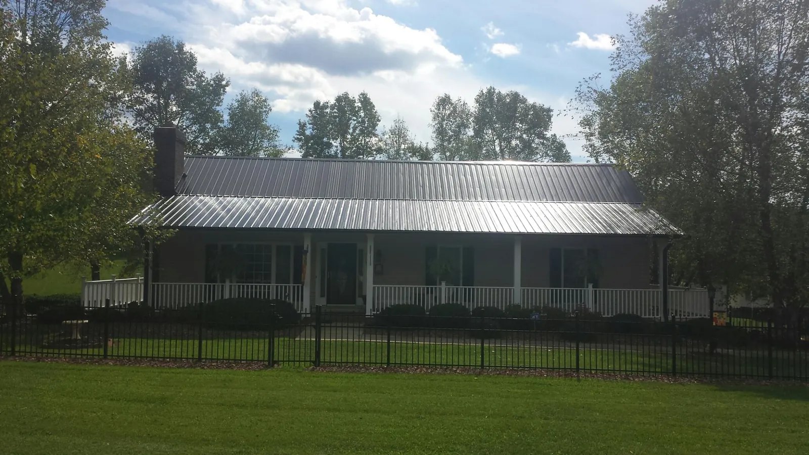 Gray metal roof on a brick ranch with a full width front porch — Gutter Guard Installation work by our crew in La Center
