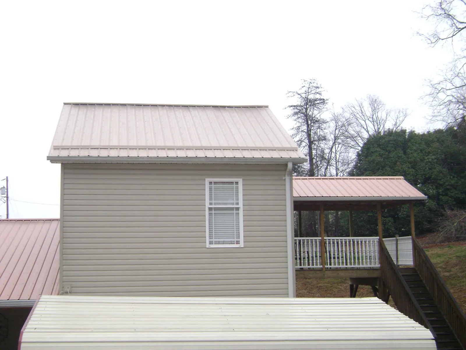 Tan metal roofs on a two story addition and attached porch, from a Roof Replacement job in La Center