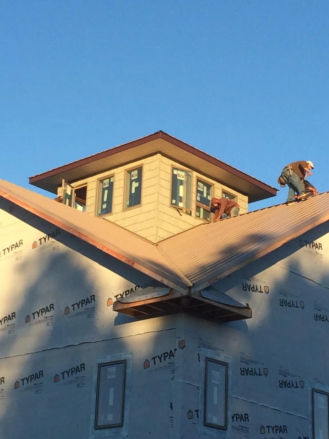 Roofers working around a rooftop cupola on a new metal roof at sunset — Roof Waterproofing in La Center by Roofing Brothers